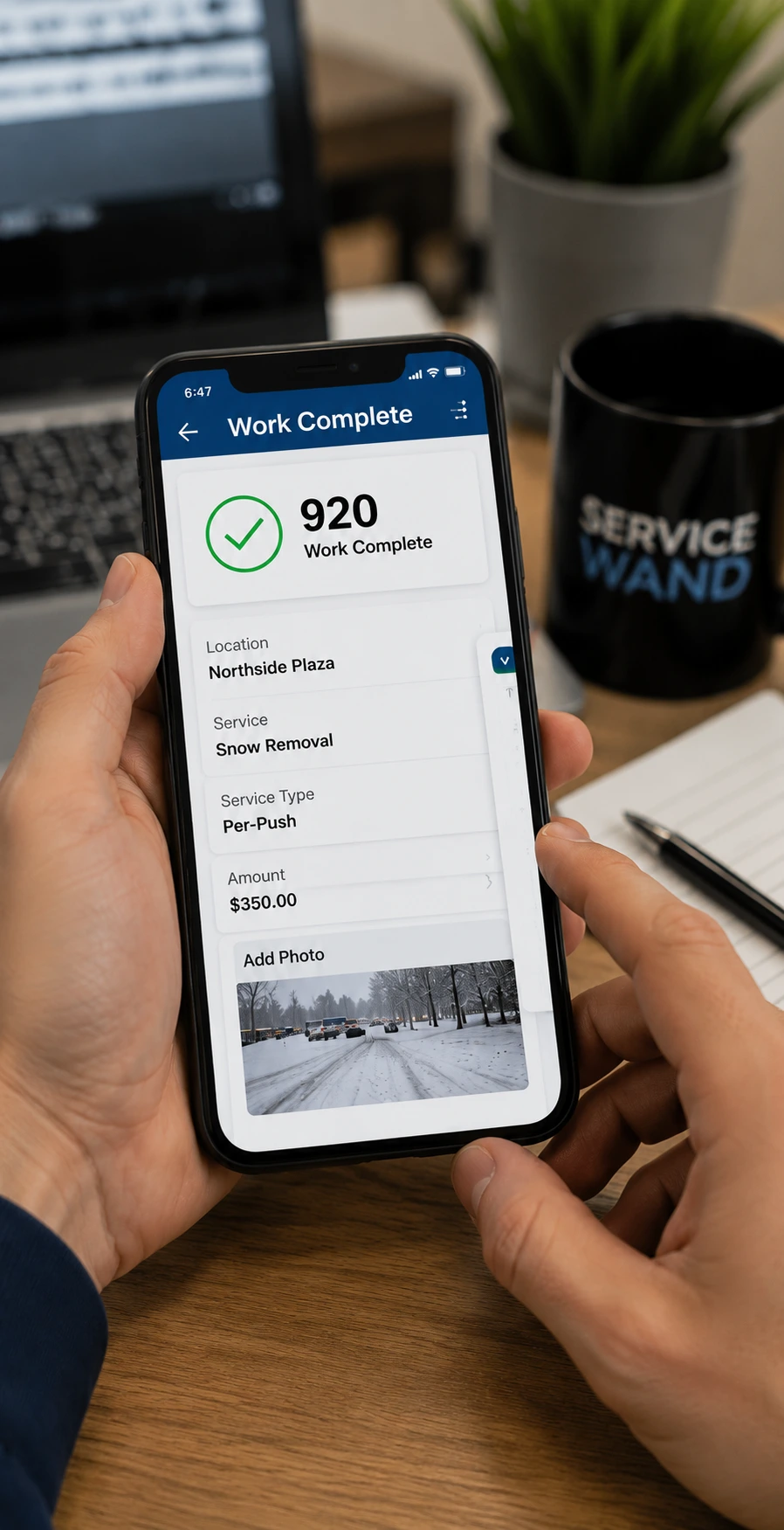 Worker using snow removal billing software on a mobile app with a desktop dashboard in the background showing completed jobs, invoice status, customer records, payment updates, and billing details